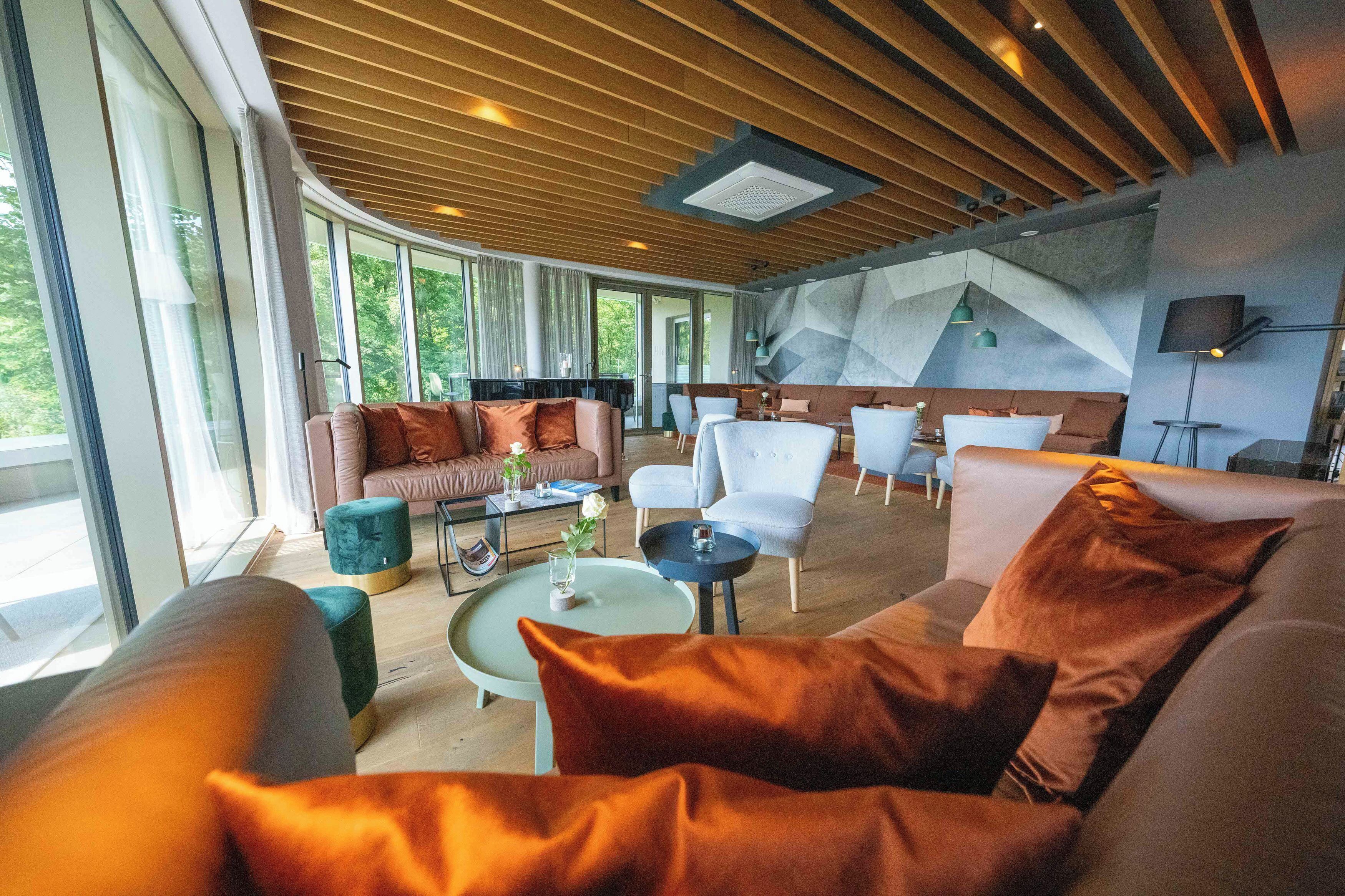 A spacious living area with a modern design, featuring a large sofa, a coffee table, and a seating area with chairs.