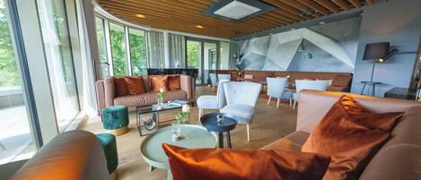 A spacious living area with a modern design, featuring a large sofa, a coffee table, and a seating area with chairs.