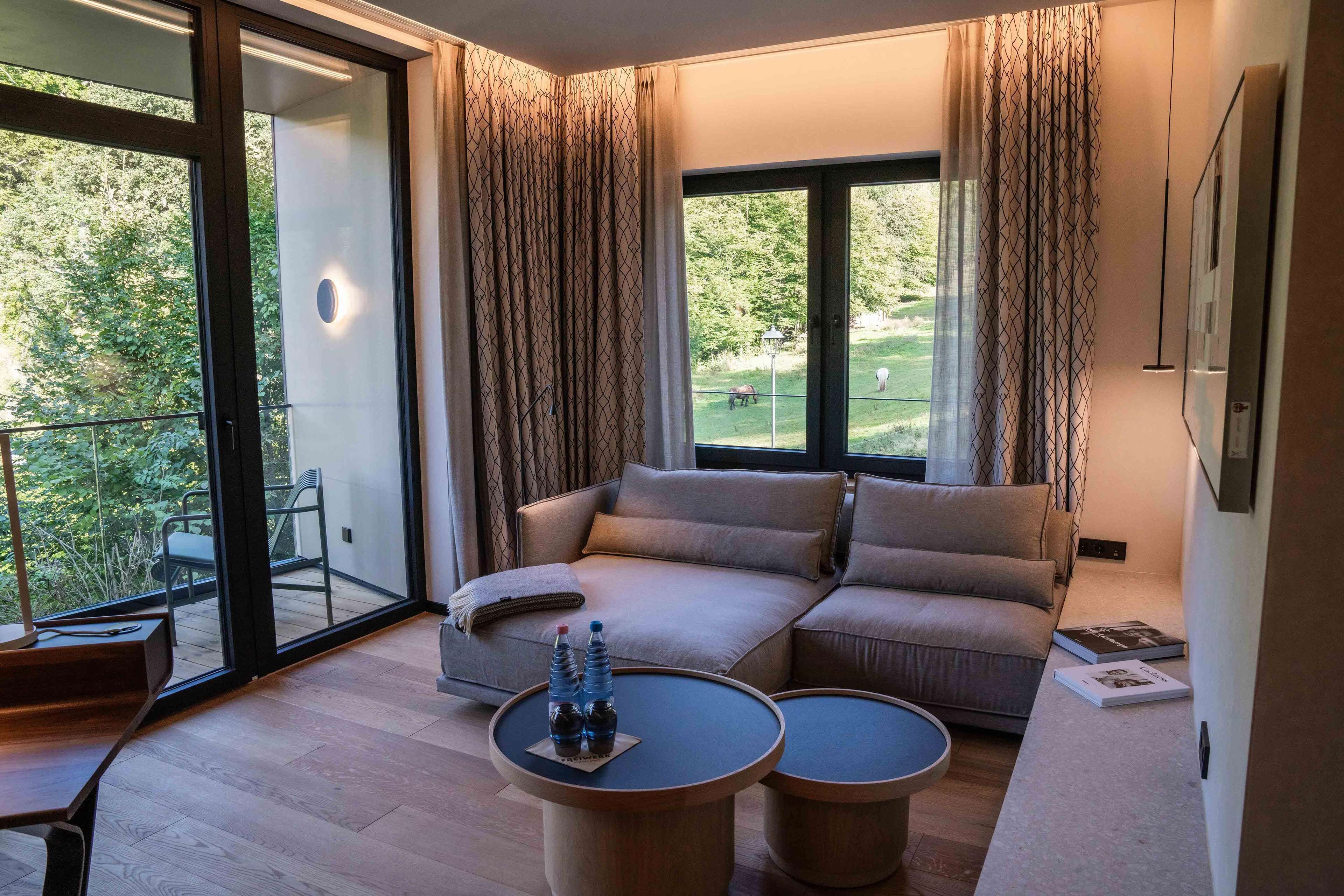 A modern living room with a sofa, two side tables, and a glass door leading to a balcony.