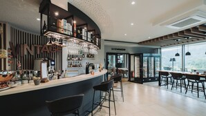 Un área de bar moderna con una barra curva, taburetes y una estantería para vinos.