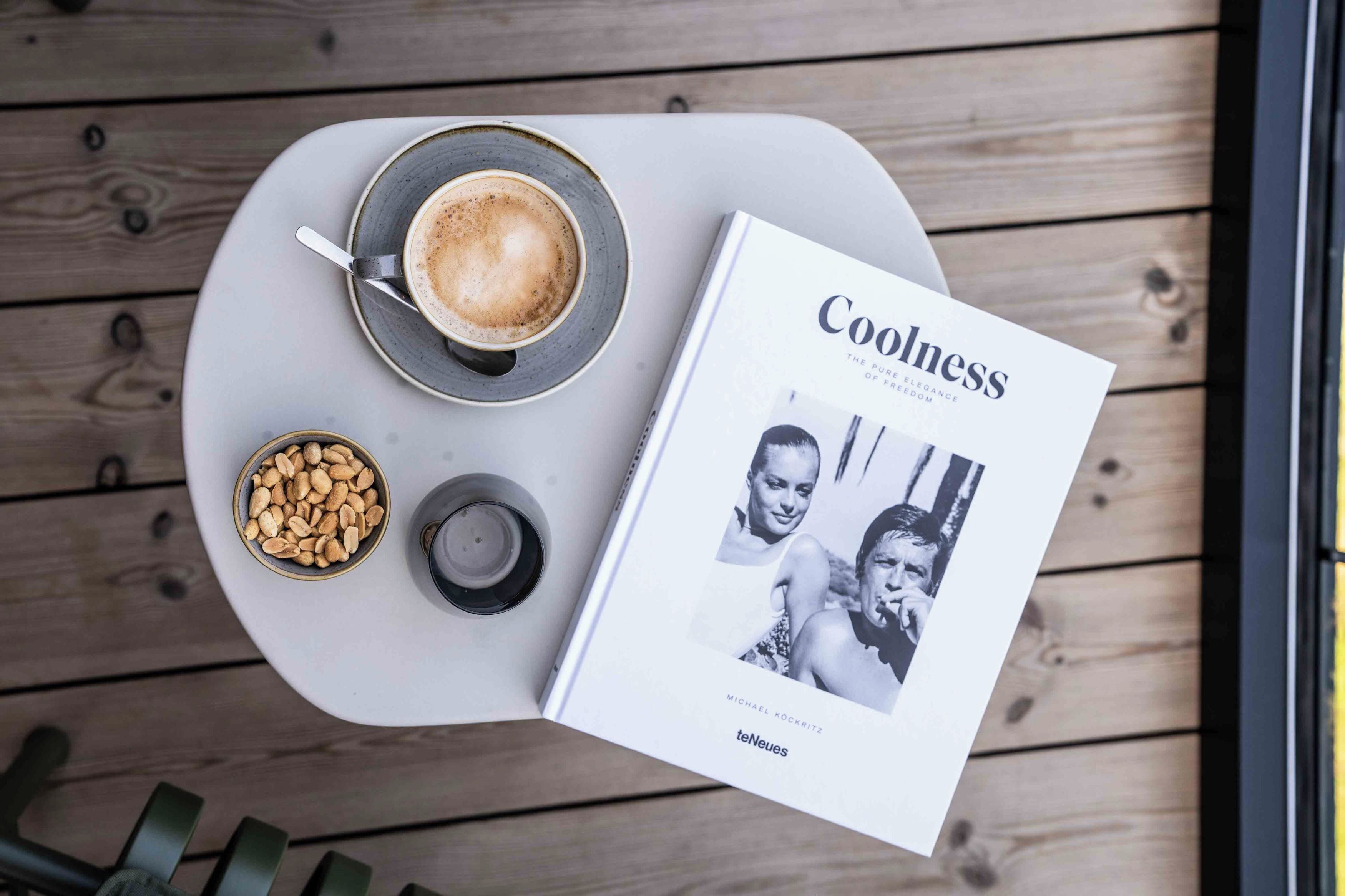 Una mesa con una taza de café, un cuenco de nueces y una revista titulada 'Coolness'.