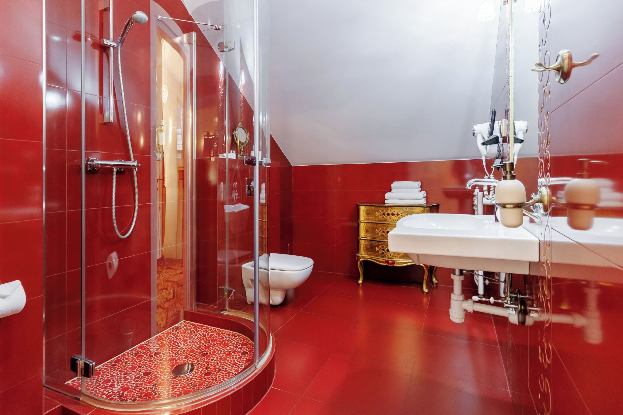 Ein modernes Badezimmer mit einer gläsernen Dusche, einer weißen Toilette und einem goldenen Waschtisch mit weißem Waschbecken.