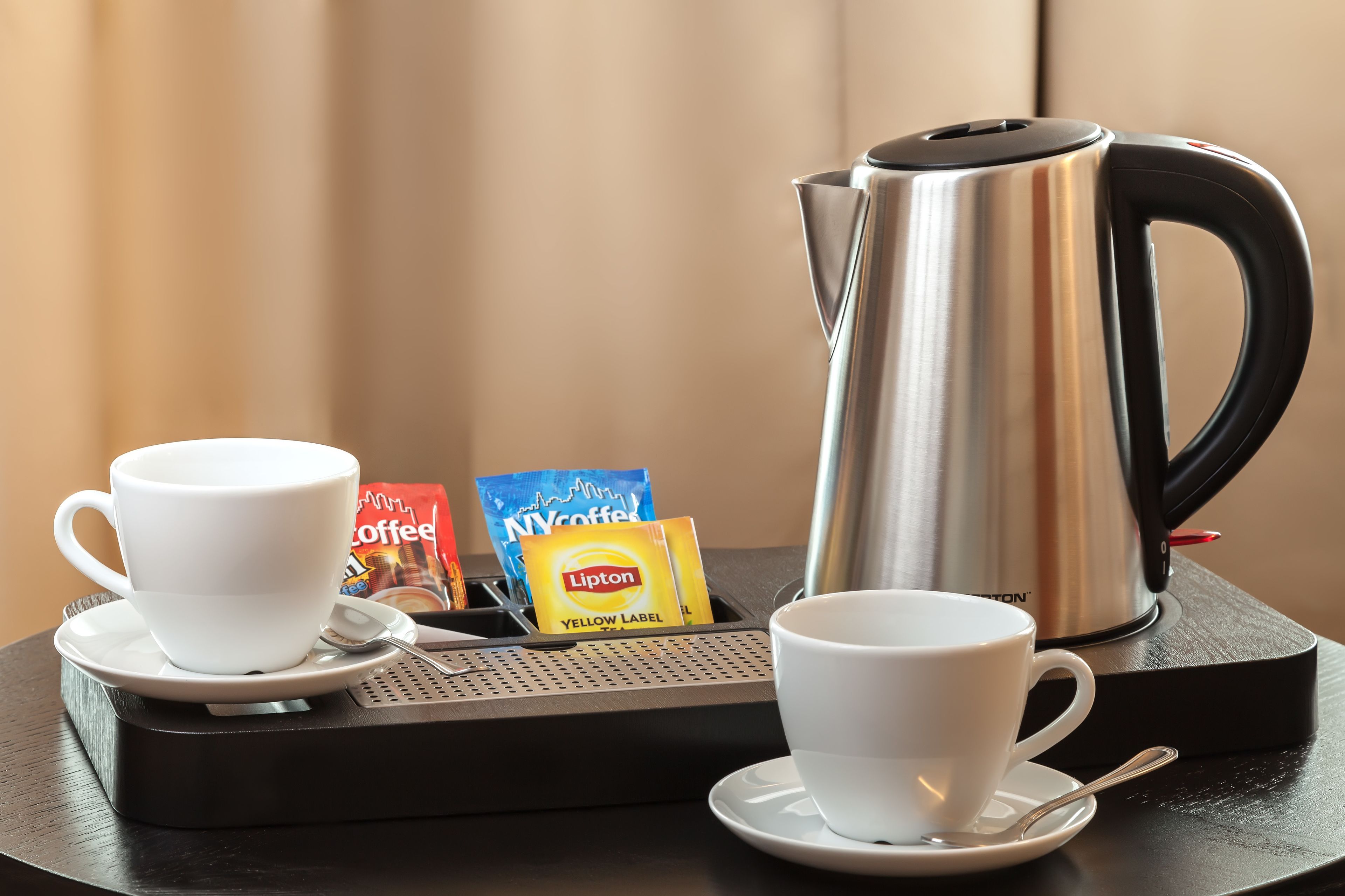 Un coin café avec deux tasses blanches, une machine à café et des sachets de café et de thé Lipton.