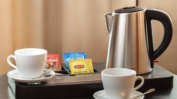 Un coin café avec deux tasses blanches, une machine à café et des sachets de café et de thé Lipton.