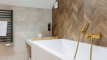A modern bathroom with a freestanding bathtub, a towel rack, and a wooden-patterned wall.