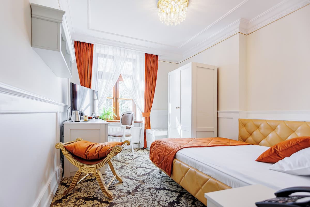 Une chambre d’hôtel comprenant un lit, un bureau, une chaise, une télévision et une armoire.