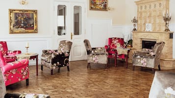 Um quarto com poltronas estampadas com flores, piso de parquet de madeira, lareira e um quadro na parede.