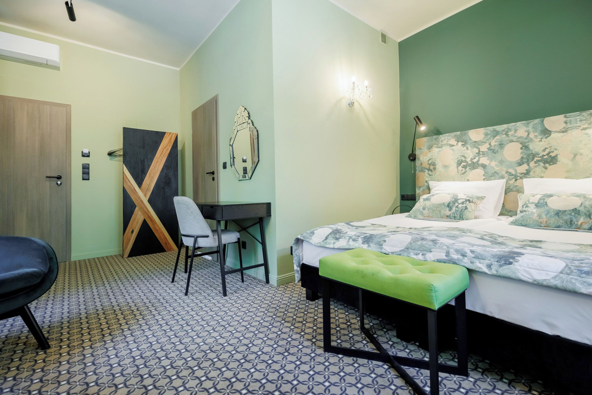 Una habitación de hotel con una cama, un escritorio, una silla y un banco.