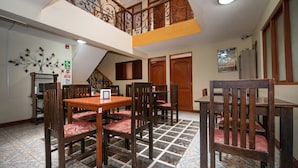 A dining area with a high ceiling, a staircase, and a decorative wall. - Ayenda Posada Inn (Cusco)