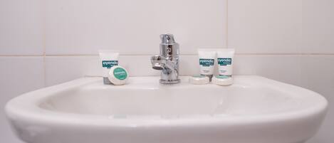 A white bathroom sink with a chrome faucet and three toiletries labeled 'ayenda'.