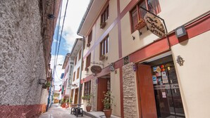 A narrow street with buildings on either side, a Posada Inn, and a visible Visa sign. - Ayenda Posada Inn (Cusco)