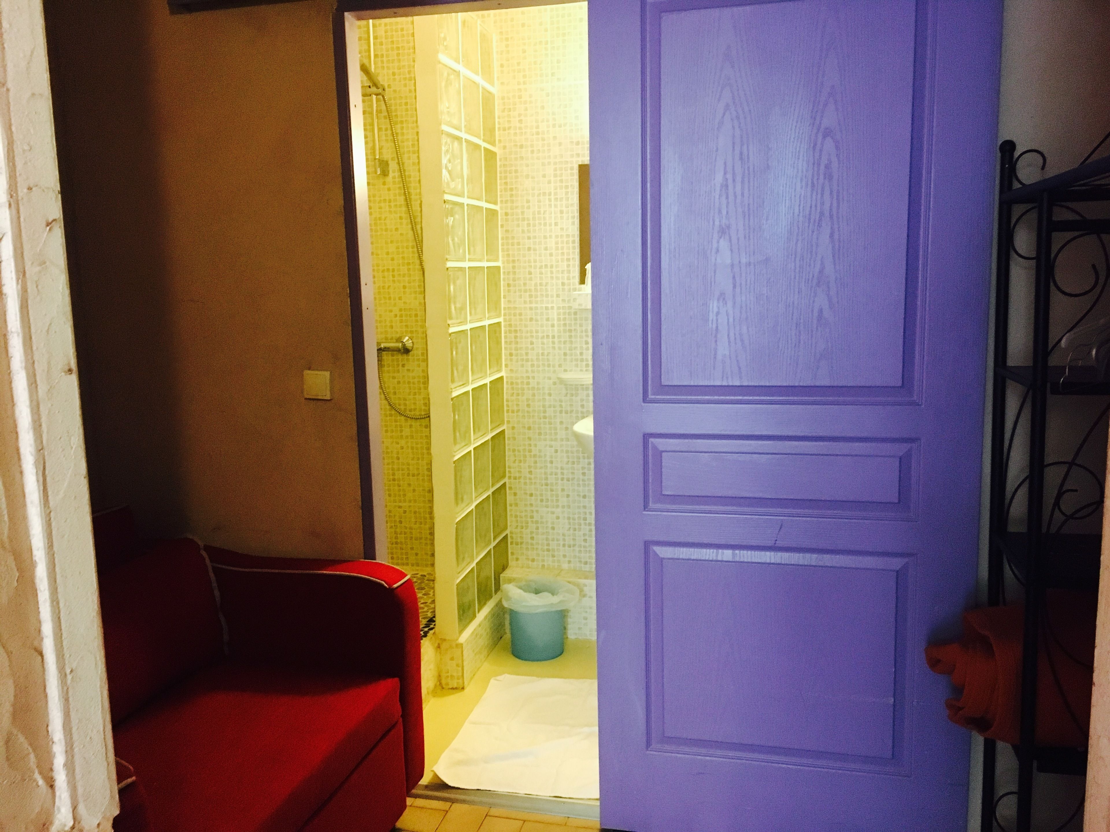 Un bagno con doccia, un water e una sedia rossa.