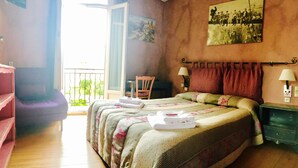 A bedroom with a bed, a chair, a balcony, and a painting on the wall. - Boutique Hôtel Couleurs du Sud (Cannes)