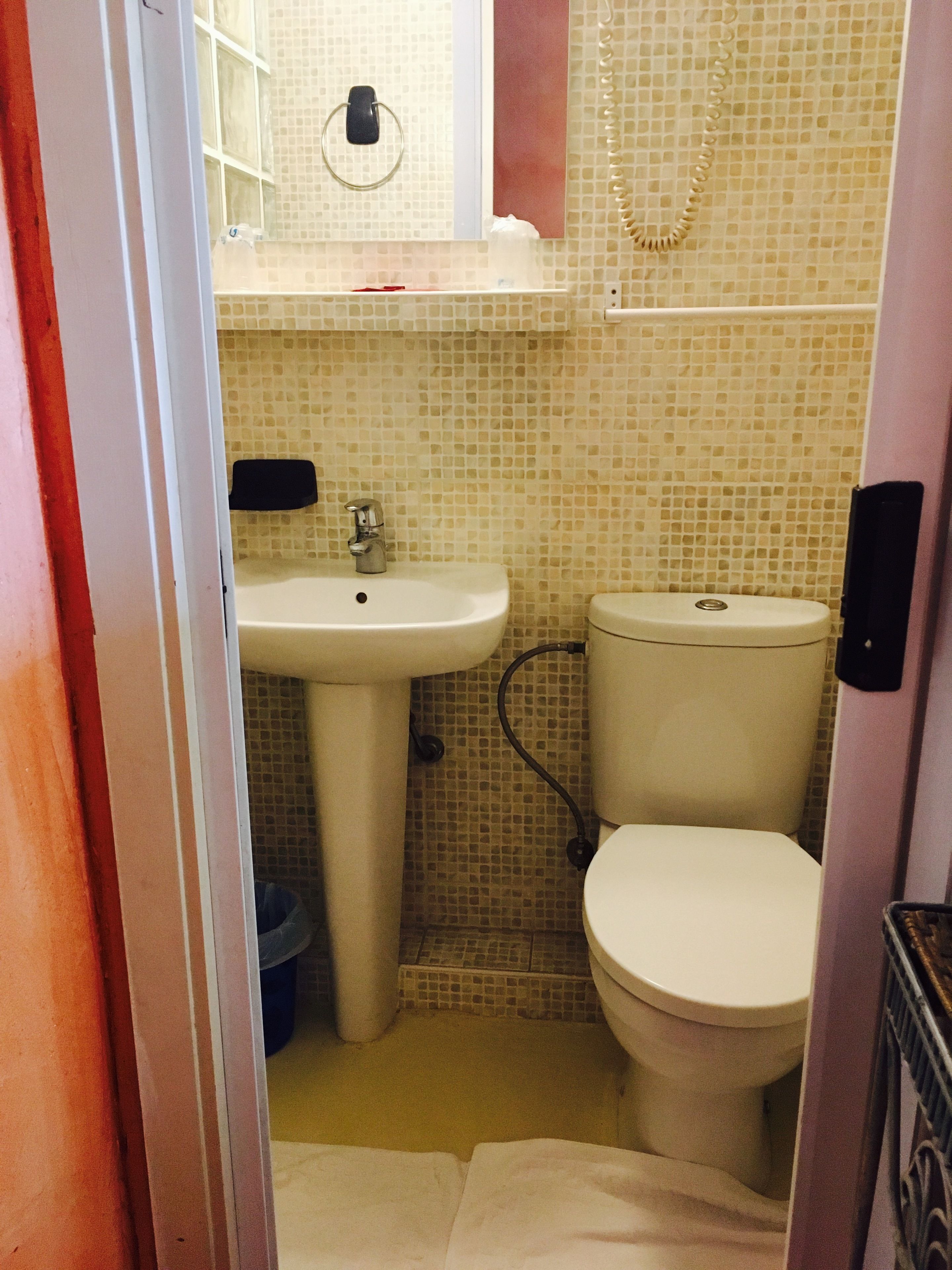 Une salle de bain avec un lavabo blanc, des toilettes et des murs carrelés.