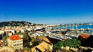 A coastal cityscape with a marina filled with boats, historic buildings, and a clear blue sky. - Boutique Hôtel Couleurs du Sud (Cannes)