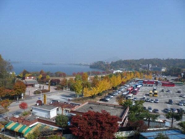 A parking lot with several buses and cars, surrounded by autumn-colored trees and buildings. - Gyerim Sanjang Motel (Chuncheon)