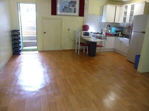 Een compacte keuken met een eettafel, stoelen, een koelkast en een magnetron.