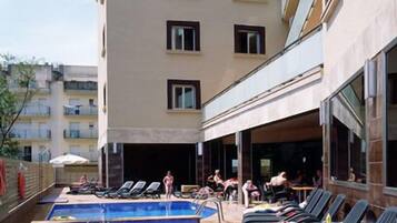 Una piscina al aire libre, sombrillas, tumbonas