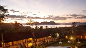 Une piscine avec vue sur l’océan et les montagnes, au crépuscule.