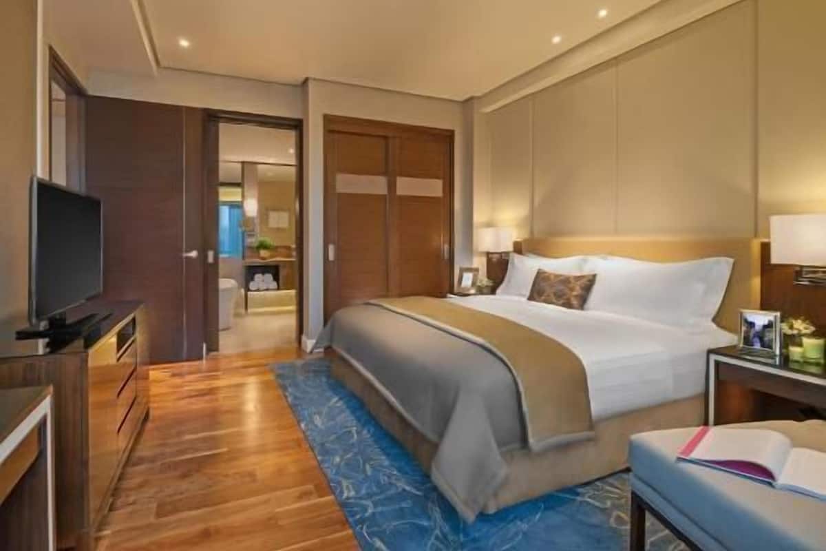 A hotel room with a bed, a television, a desk, and a bathroom visible through an open door.