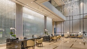Un moderno vestíbulo de hotel con mostrador de recepción, zona de estar y amplias ventanas.