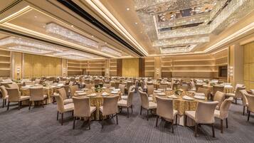 Un amplio salón de banquetes con mesas redondas, sillas y candelabros.