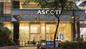 Un edificio moderno con fachada de vidrio y el nombre "ASSCOTT" en grande.