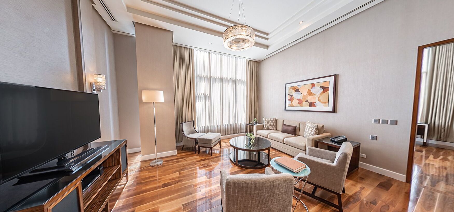 A modern living room with a flat-screen TV, a sofa set, a coffee table, and a floor lamp.