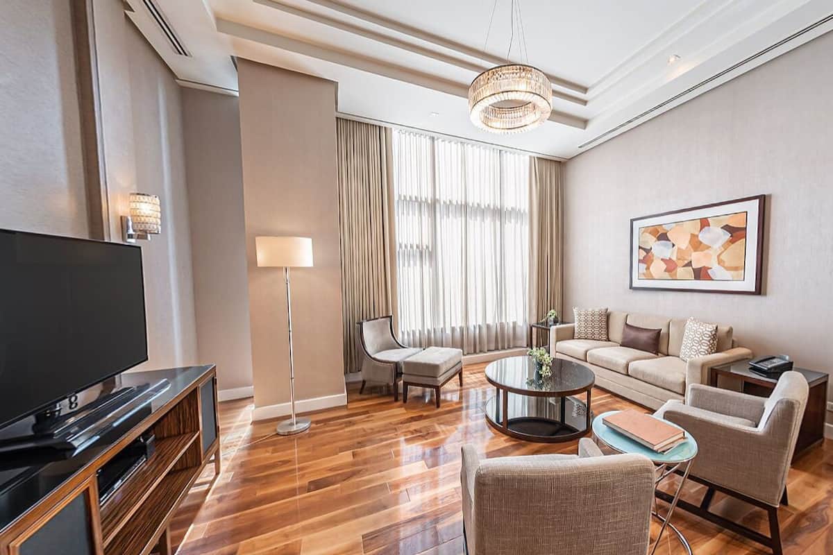 A modern living room with a flat-screen TV, a sofa set, a coffee table, and a floor lamp.