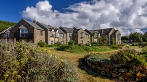 Una hilera de casas de piedra con múltiples ventanas y un área verde al frente.