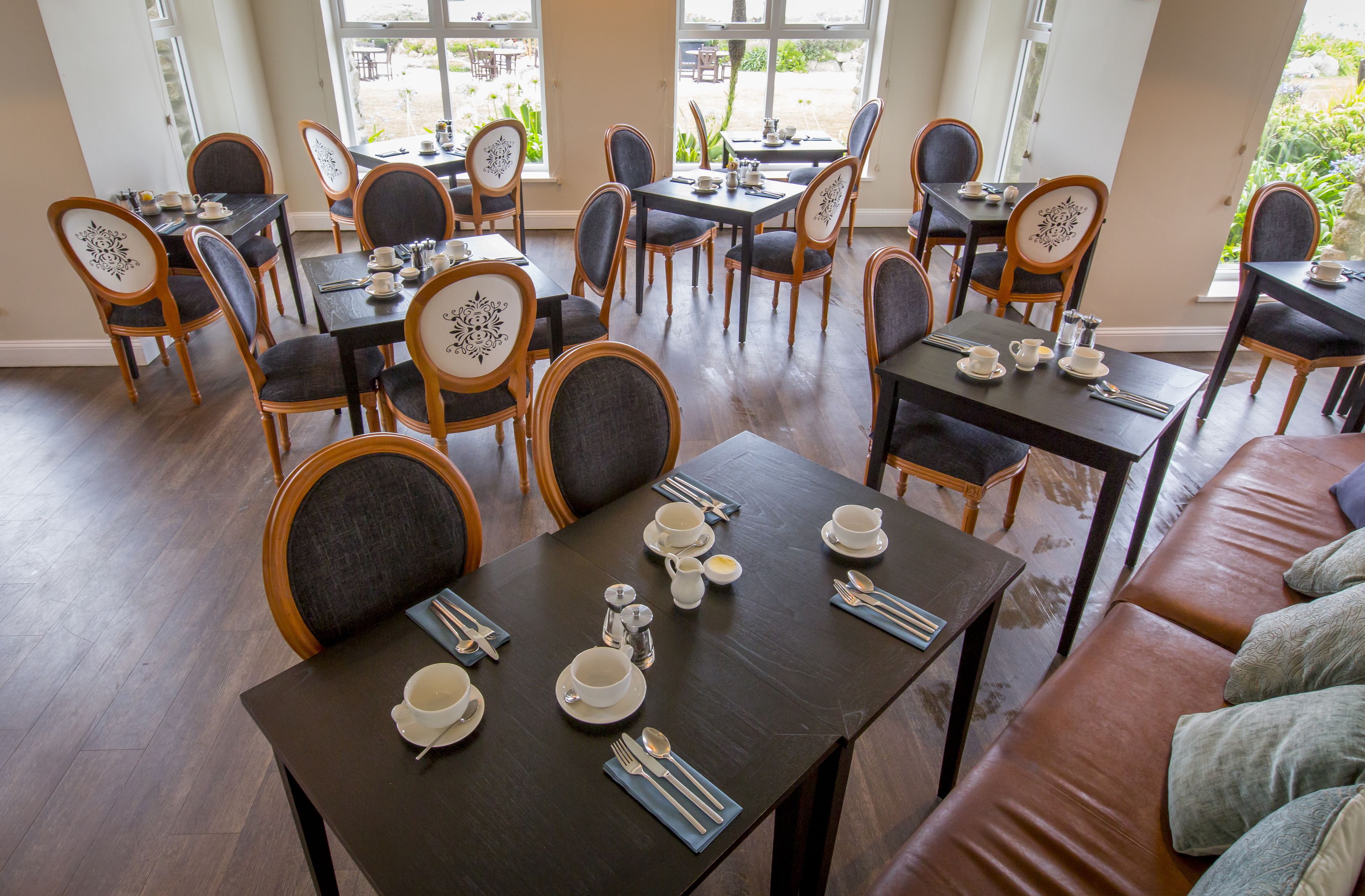 A dining area with multiple tables and chairs, some with floral designs on the backrests.