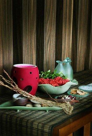 A wooden table with a red ceramic mug, a green bowl with red flowers, and a green pitcher. - favehotel Graha Agung Surabaya (Surabaya)