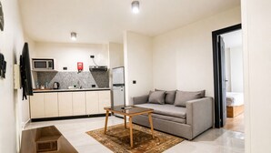A compact living space with a kitchenette, a sofa, a coffee table, and a bed. - NewCity Hotel & Suites (New Cairo)