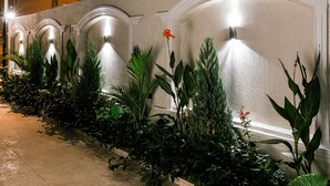 A pathway lined with plants and a wall with arched lighting fixtures. - NewCity Hotel & Suites (New Cairo)