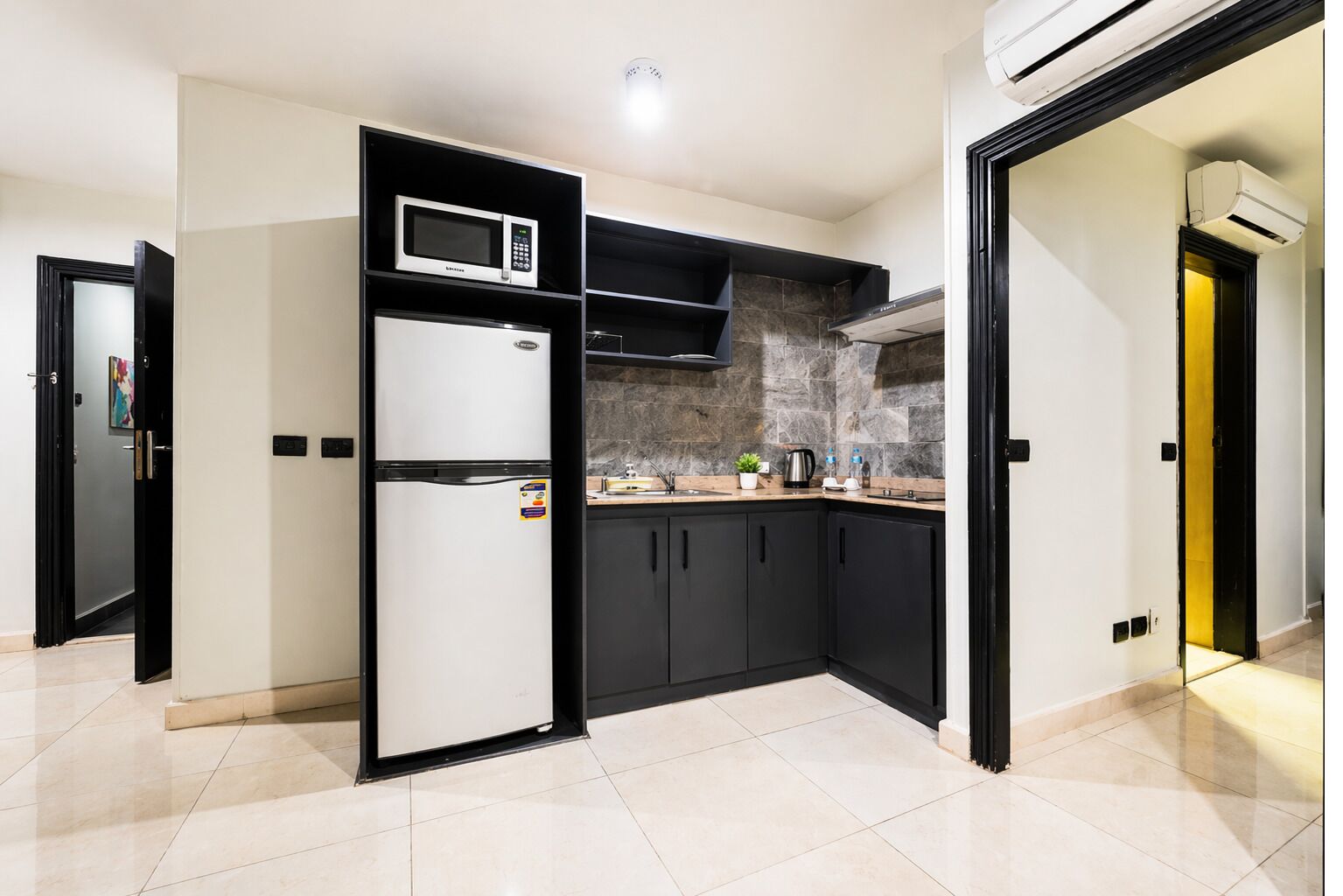 A modern kitchen with a built-in microwave, a refrigerator, and a stone backsplash.