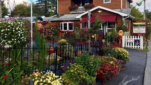 A wooden house with a porch, surrounded by a variety of flowers and plants.