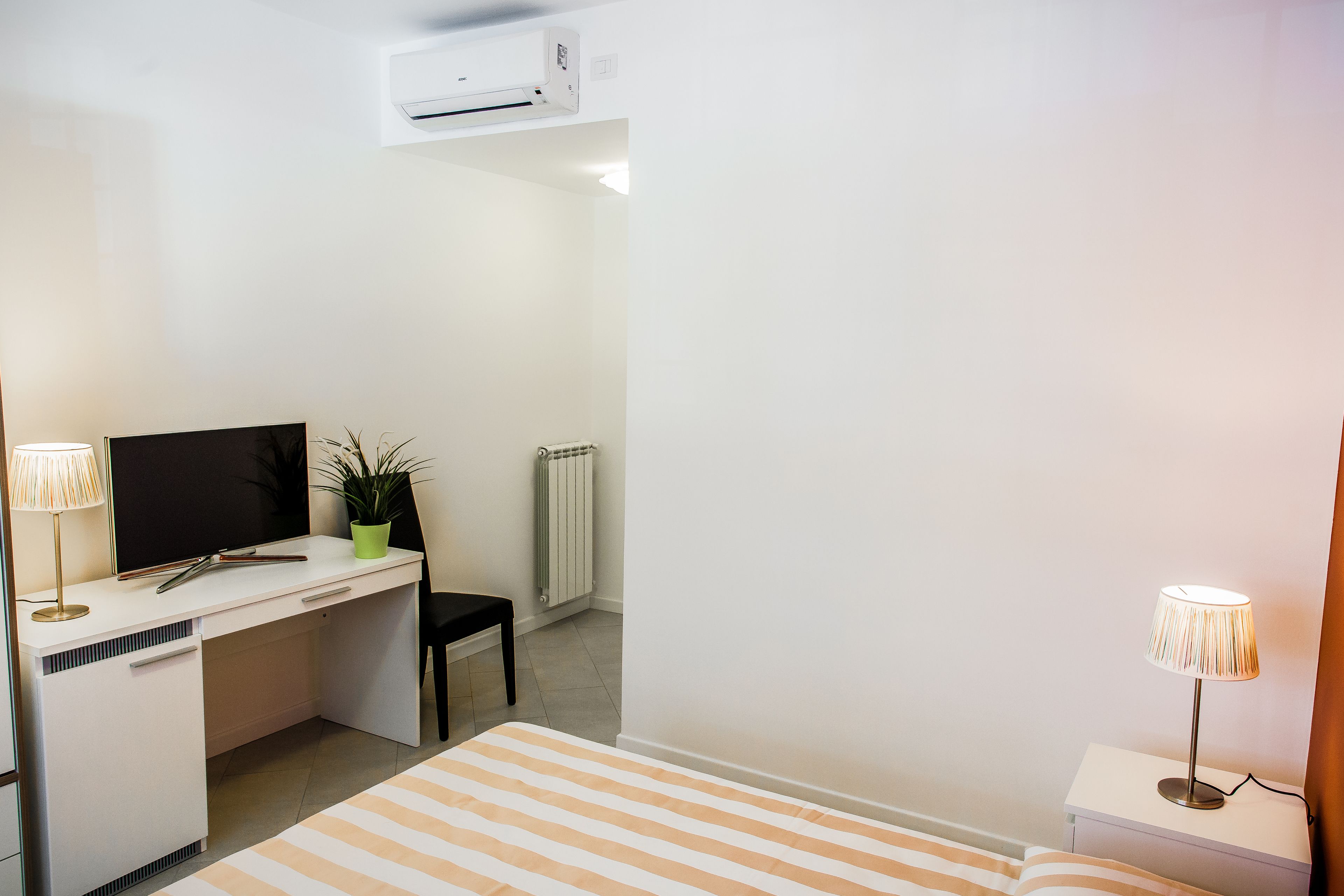 Une chambre à coucher avec un lit, un bureau, une chaise, un téléviseur et un radiateur.