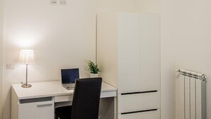 A compact room with a white desk, a chair, a laptop, a radiator, and a wardrobe. - Vatican Rooms Holiday in Rome (Rome)