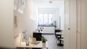 A modern kitchen with white cabinets, a dining area with a round table, and a laptop on a desk. - Vatican Rooms Holiday in Rome (Rome)