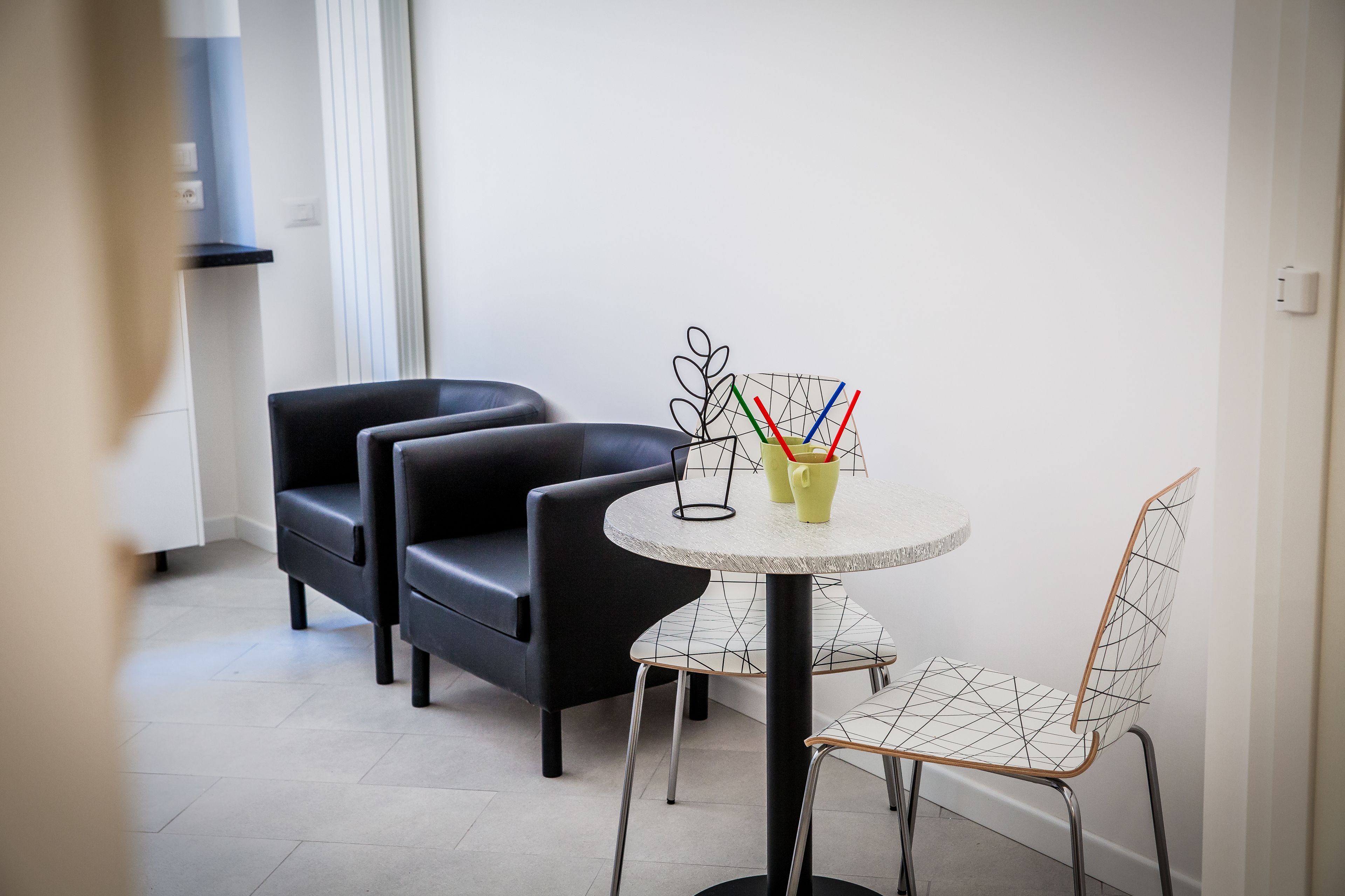 A modern room with a round table, two black chairs, and a metal chair with a geometric design.