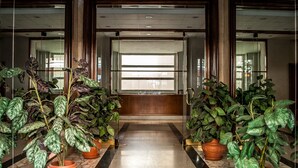 A hallway with potted plants, marble flooring, and a glass door at the end. - Vatican Rooms Holiday in Rome (Rome)