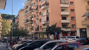 A multi-story residential building with balconies, parked cars, and a street sign. - Vatican Rooms Holiday in Rome (Rome)
