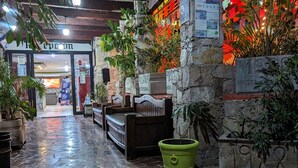 Entrada de un hotel con fachada de piedra, un cubo verde y un cartel que indica el año 1988.