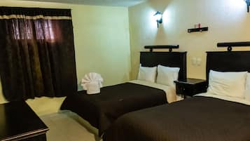 A hotel room with two beds, a nightstand, a lamp, and a curtain.