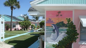 A beachfront property with a painted mural of a dolphin, a swimming pool, and a well-maintained lawn. - Sea Scape Oceanfront Motel (Indialantic)