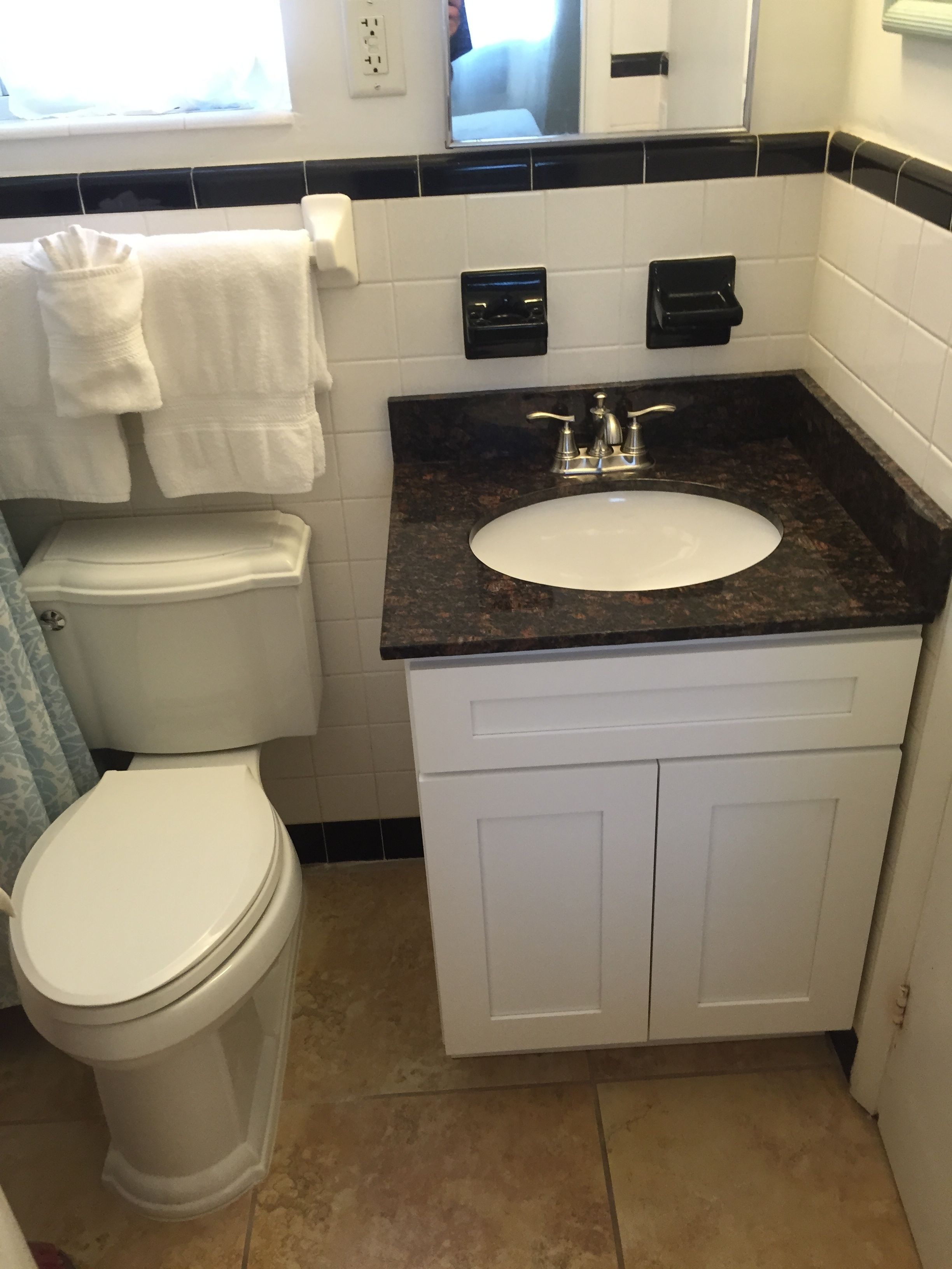 A bathroom with a white toilet, a sink with a black countertop, and a mirror above the sink.