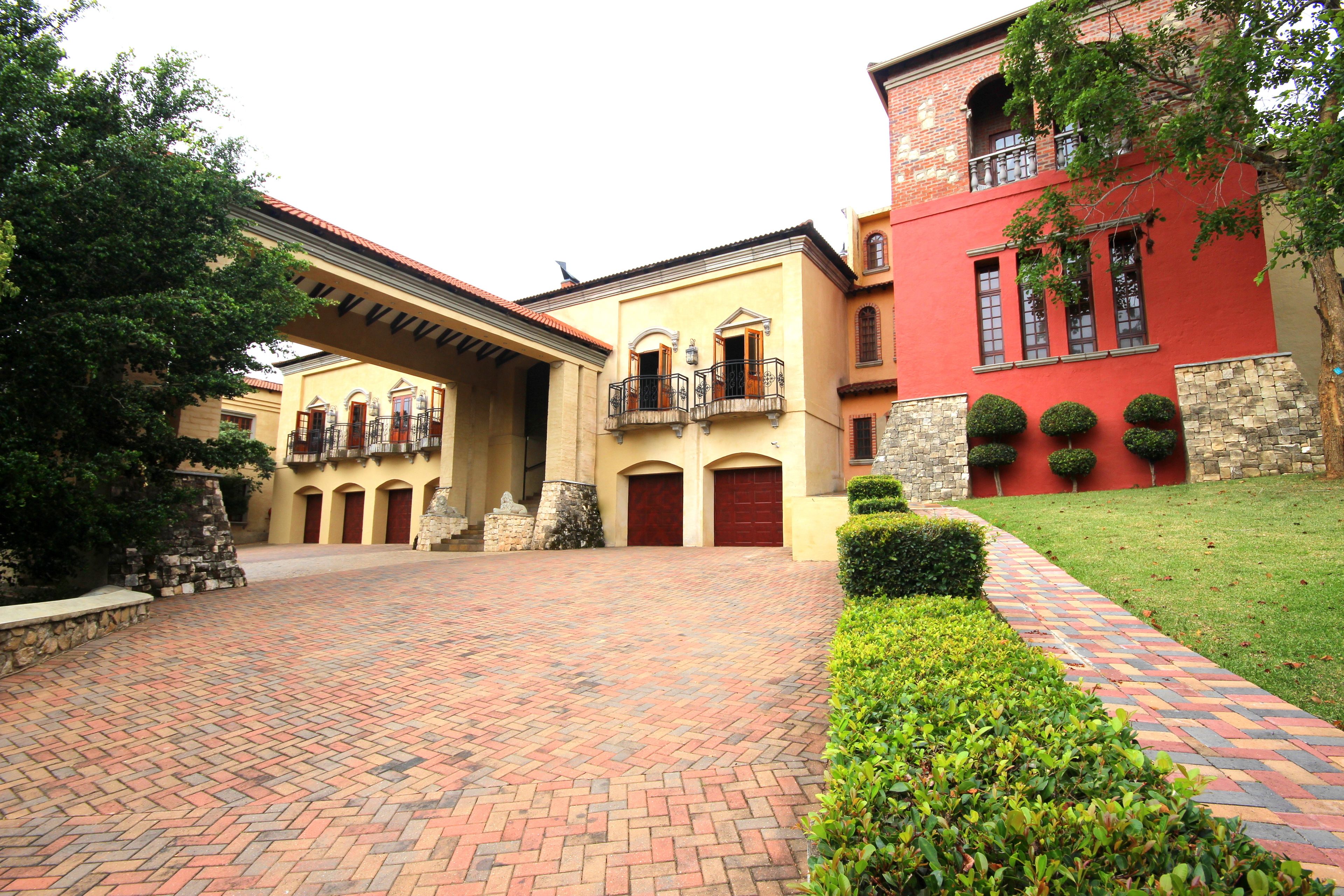 A courtyard with a brick pathway, a yellow building with red doors, and a red building with a balcony.