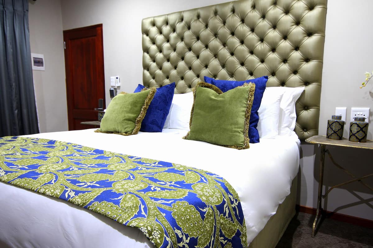 A hotel room with a large bed, a tufted headboard, and a nightstand with a vase of flowers.