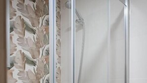 A glass-enclosed shower with a white toilet visible through the glass. - San Antonio (Madrid)