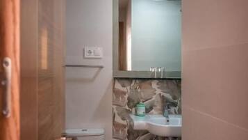 Een badkamer met toilet, wastafel en spiegel.